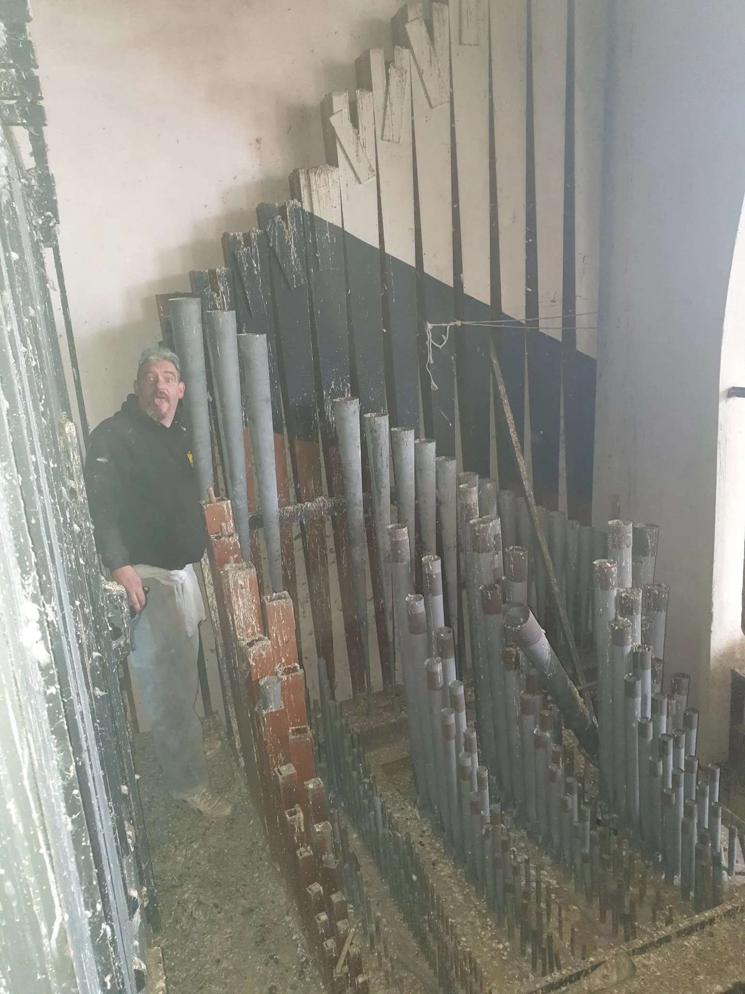 A man standing next to a bunch of pipes.