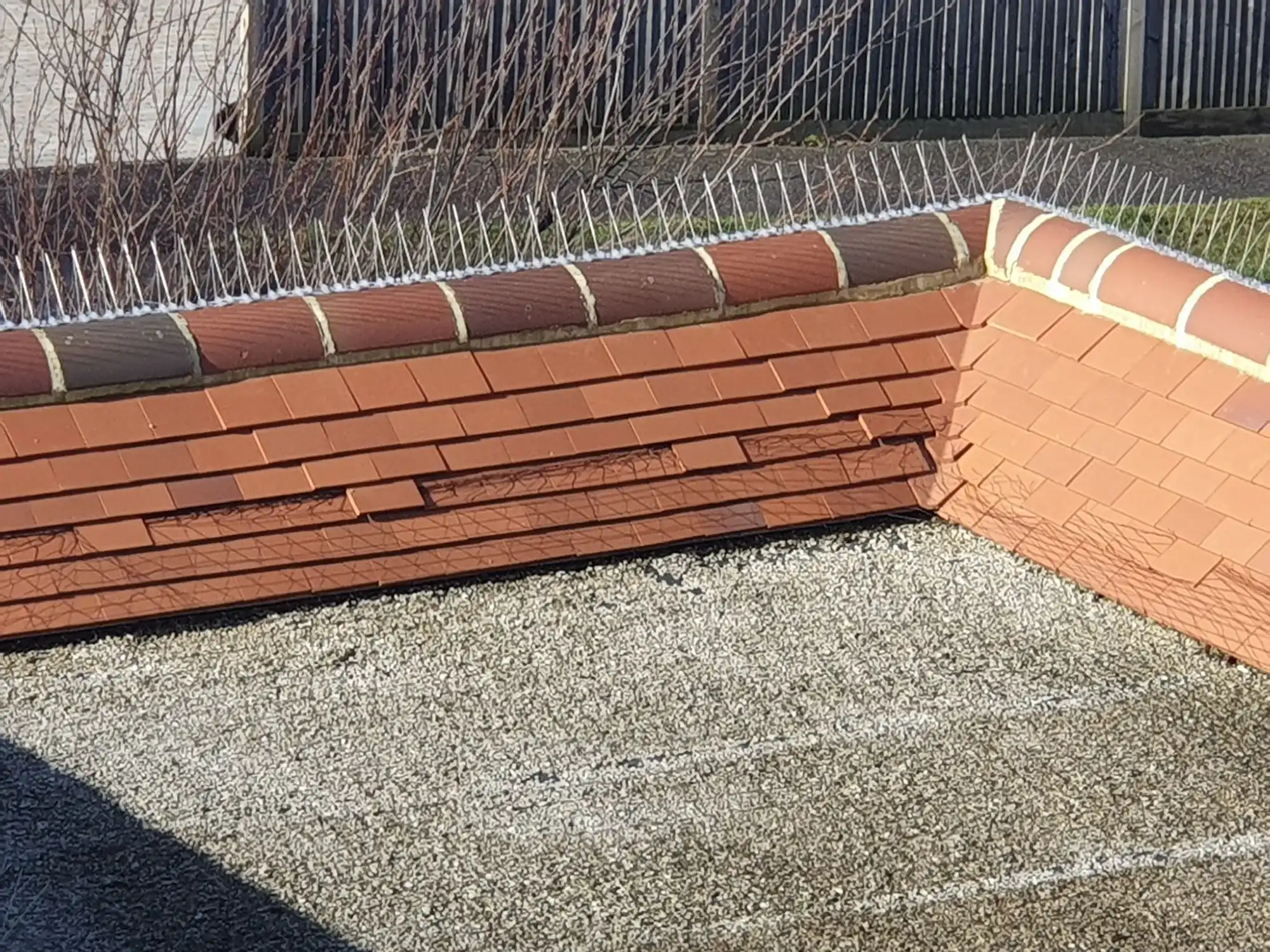 A brick planter with a chain link fence around it.