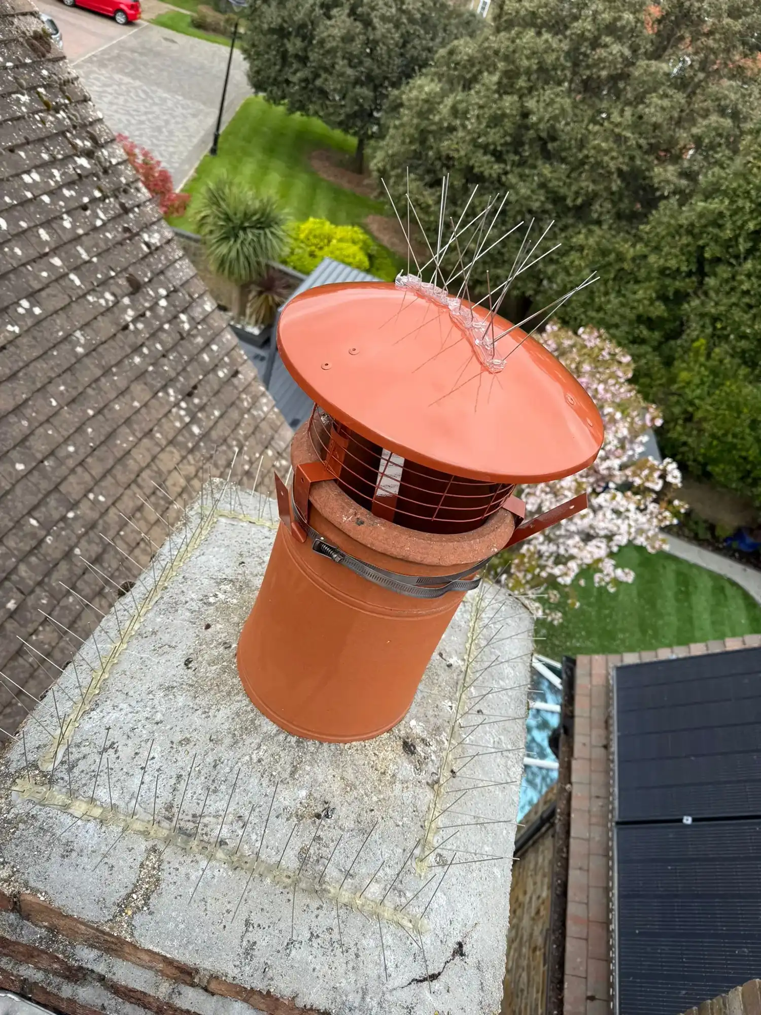 An orange chimney on the roof of a house.